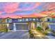 Charming two-story home featuring a tile roof, brick driveway, and manicured landscaping, illuminated by pathway lighting at 12816 Alcores St, Las Vegas, NV 89141