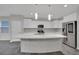 A bright kitchen features a large kitchen island, white cabinets, and stainless steel appliances at 12816 Alcores St, Las Vegas, NV 89141