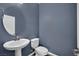 A cozy powder room with blue walls, pedestal sink, round mirror, and modern toilet at 12816 Alcores St, Las Vegas, NV 89141