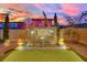 Backyard featuring a modern tiled water feature with three waterfalls, set against a colorful sunset sky at 12816 Alcores St, Las Vegas, NV 89141