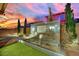 Backyard featuring a modern tiled water feature with three waterfalls, set against a colorful sunset sky at 12816 Alcores St, Las Vegas, NV 89141