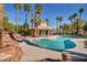 Community pool area featuring lounge seating, palm trees, and rock waterfall feature at 2107 Eaglepath Cir, Henderson, NV 89074