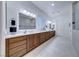 Bathroom with double sinks, wood cabinets, a large mirror, and a walk-in shower at 2239 Discovery Lake Ct, Henderson, NV 89044