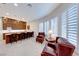 Bright living room with large windows, shutters, a bar counter with seating, and two leather chairs at 2239 Discovery Lake Ct, Henderson, NV 89044