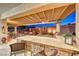 Outdoor kitchen with built-in barbecue, bar seating, pergola, travertine tile and seating area at 2239 Discovery Lake Ct, Henderson, NV 89044