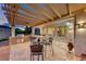 Outdoor kitchen with built-in barbecue, bar seating, pergola, and travertine tile with adjacent seating area at 2239 Discovery Lake Ct, Henderson, NV 89044