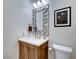 Stylish powder room features a decorative mirror, modern lighting, and wood cabinet with a white countertop at 2239 Discovery Lake Ct, Henderson, NV 89044