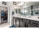 Bathroom featuring double sinks, gray cabinets, large mirrors, and a walk-in closet at 306 Dedication Ave, Henderson, NV 89011