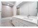 Modern bathroom featuring double sinks, white cabinets, marble counters, and a shower-tub combo at 5015 Terramont Dr, Las Vegas, NV 89135