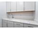 Bright laundry room features white cabinetry, quartz countertops, and stainless steel hardware at 5015 Terramont Dr, Las Vegas, NV 89135