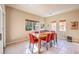 Bright dining room with wood table, six red chairs, tile floors, natural light, and contemporary artwork on walls at 5891 Alfano Ave, Pahrump, NV 89061