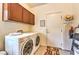 Well-lit laundry room features washer, dryer, storage cabinets, and space-saving ironing board at 5891 Alfano Ave, Pahrump, NV 89061