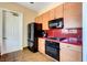 Kitchen with black appliances, tan wood cabinets, and red countertop at 5965 Poplar Tree St, Las Vegas, NV 89148