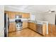 Kitchen with stainless appliances, wood cabinetry, and hardwood floors, open to the living area at 6116 Casa Antiqua St, North Las Vegas, NV 89081