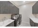 Laundry room with gray cabinets, stainless steel washer and dryer, and a modern sink at 6832 Apogee Ridge Ct, Las Vegas, NV 89135