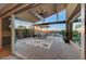 Covered outdoor patio with a built-in kitchen, stone flooring, and a view of the landscaped backyard and pool at 6832 Apogee Ridge Ct, Las Vegas, NV 89135