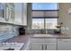 Close-up of kitchen countertop with white cabinets, large window, and modern appliances at 7608 Little Valley Ave, Las Vegas, NV 89147