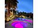 Nighttime view of the backyard pool and hot tub, illuminated with colorful lights and tropical landscaping at 8145 Mountain Forest Ct, Las Vegas, NV 89129