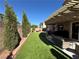 Landscaped backyard featuring artificial turf, a covered patio, and mature trees for added privacy at 9364 Olympia Falls Ave, Las Vegas, NV 89149