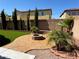 Serene backyard oasis featuring a stone fire pit, artificial grass, and lush palm trees at 9364 Olympia Falls Ave, Las Vegas, NV 89149