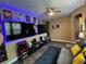 Modern living room featuring gaming setup, blue accent lighting, ceiling fan, and wood-look flooring at 9364 Olympia Falls Ave, Las Vegas, NV 89149