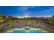 Night view of backyard featuring pool, hot tub, palm trees, and city skyline in the distance at 9795 La Cienega St, Las Vegas, NV 89183