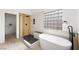 A luxury bathroom featuring a modern soaking tub, a tiled shower, and a unique glass-block window for natural light at 9795 La Cienega St, Las Vegas, NV 89183