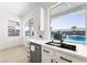 Modern white kitchen with stainless appliances and a window view of the backyard swimming pool at 9795 La Cienega St, Las Vegas, NV 89183