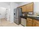 View of the kitchen featuring wood cabinets, stainless steel refrigerator and dishwasher, and tiled walls at 10651 Streamside Ave, Las Vegas, NV 89129