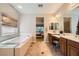 Bathroom with soaking tub, dual sinks, tile floors, and view into the bedroom at 11165 Robin Park Ave, Las Vegas, NV 89138