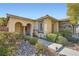 Beautiful single-story home with an arched entryway, stone accents, and mature desert landscaping at 11165 Robin Park Ave, Las Vegas, NV 89138