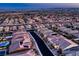 This aerial view shows a community of homes with tile roofs and a city skyline at 11831 Saverio Ave, Las Vegas, NV 89138