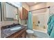 Bathroom with a granite-topped vanity, wooden cabinet, and a tub-shower combination with a blue shower curtain at 1464 Barlow Ave, Moapa, NV 89025