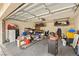 Cluttered garage filled with household items, storage boxes, and a work bench with shelves at 1851 Hillpointe Rd # 2922, Henderson, NV 89074