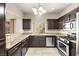 Kitchen featuring granite countertops, stainless steel appliances, dark wood cabinets, and natural light at 1851 Hillpointe Rd # 2922, Henderson, NV 89074