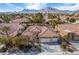 Daytime aerial view of a home's exterior with a three-car garage, desert landscaping, and mountains in the background at 2329 Quartz Peak St, Las Vegas, NV 89134