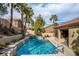 Beautiful backyard pool with a waterfall feature, surrounded by mature palm trees and lush greenery, creating a private oasis at 2329 Quartz Peak St, Las Vegas, NV 89134