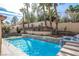 A beautiful pool with a spa and waterfall feature with lush tiered landscaping and palm trees in the backyard at 2329 Quartz Peak St, Las Vegas, NV 89134