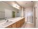 Bathroom featuring double sinks, granite countertops, a large mirror, and glass shower doors at 2554 Corvus St, Henderson, NV 89044