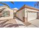 Beige single-story home featuring a two-car garage, desert landscaping, and covered front porch entrance at 2554 Corvus St, Henderson, NV 89044