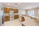 Bright open kitchen area with white appliances, wood cabinets, and a breakfast bar overlooking the living area at 2554 Corvus St, Henderson, NV 89044