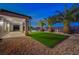 Inviting backyard features a covered patio, synthetic grass, palm trees, and a sparkling pool at twilight at 2820 Thunder Bay Ave, Henderson, NV 89052