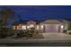 Night shot of single-story home with well-lit exterior, desert landscaping, and an attached garage at 2820 Thunder Bay Ave, Henderson, NV 89052