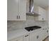 Modern kitchen featuring white cabinetry, a stone backsplash, and stainless steel hood at 2820 Thunder Bay Ave, Henderson, NV 89052