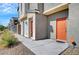 Modern townhome row featuring desert landscaping and bright orange front doors along a sidewalk at 4566 Ganier Ct # 1125, North Las Vegas, NV 89031