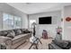 Comfortable living room featuring a gray sofa, large windows, neutral walls, and a mounted flat screen television at 4566 Ganier Ct # 1125, North Las Vegas, NV 89031