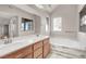 Bright bathroom featuring double sinks, soaking tub with marble accents, and natural light from large windows at 4722 Obannon Dr # D, Las Vegas, NV 89102