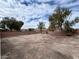 Spacious backyard with a dirt lot, framed by a low brick wall and trees at 4928 Indigo Gorge Ave, Las Vegas, NV 89131