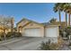 Front exterior showcasing a three-car garage, neutral paint, and beautiful landscaping with palm trees at 5022 Arizo Ct, North Las Vegas, NV 89031