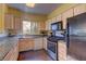 Well-lit kitchen featuring wooden cabinets and black appliances at 5250 S Rainbow Blvd # 1121, Las Vegas, NV 89118